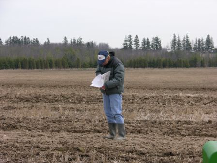 Photo of man in field making notes on paper