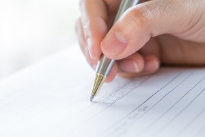 Photo of man's hand holding pen on paper